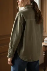Sobrecamisa de algodón peinado en color verde oliva, con corte oversize, cuello camisero, cierre frontal con botones metálicos y bolsillos frontales tipo parche.