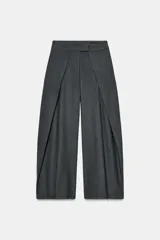 Pantalón wide leg de tiro medio color gris con raya diplomática, confeccionado en hilatura con viscosa. Cuenta con bolsillos laterales ocultos en costura, detalle de pinzas frontales y cierre con cremallera, botón y ganchos metálicos.