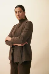 Chaqueta corta color beige, entallada, con escote en V, manga larga y bolsillos escondidos. Cierre frontal con lazo fijo. Confeccionada en lana fina sin teñir. Diseño exclusivo de Don Baez.