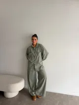 Pantalón de corte amplio y tiro alto, confeccionado en tela de viyela con estampado de cuadros en tonos verdes y neutros. Presenta una caída fluida y holgada.