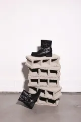 Bota corta negra de cuero con hebillas y arnés metálico.