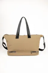 Bolso de gran capacidad color beige, con asas fijas superiores y correa de cinta negra desmontable y regulable. Presenta un bolsillo externo con cierre, un compartimento inferior con cierre y logo de la marca Daniel Cassin en el frente.