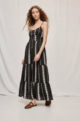 Vestido largo negro de algodón, con breteles finos, escote con frunce y lazo regulable. Tiene cintura definida y falda amplia escalonada, con detalles bordados verticales en contraste.