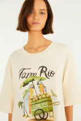 Vestido largo color crudo de corte fluido y movimiento ligero, con mangas cortas, escote redondo y estampado frontal ilustrativo con la inscripción "Farm Rio" y un puesto de cocos tropical.