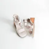 Sandalias de cuero color blanco con taco de madera y detalle de borlas.