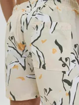 Short de baño de tiro medio con estampado botánico abstracto en tonos blanco, negro y amarillo sobre base color crema. Cuenta con cintura elástica con cordón ajustable, bolsillos laterales y bolsillo trasero.