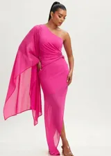 Vestido largo de fiesta color fucsia, con diseño de un solo hombro y manga tipo capa fluida. Presenta un detalle de fruncido lateral con aplique metálico en la cintura y falda con tajo lateral.
