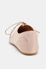 Zapato plano tipo bailarina deportiva color rosado, con cierre de cordones blancos y negros, y punta redonda. Suela de 0,5 cm de altura.