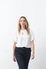 Top negro de manga corta con detalle de nudo en el escote y abertura tipo gota. Presenta una silueta relajada y textura sutil en la tela.