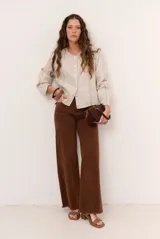 Chaqueta de lino color beige, de manga larga, con cuello redondo y cierre frontal de botones a presión con solapa.