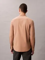 Camisa de manga larga Calvin Klein con corte slim, cuello de punta clásico, cierre frontal con botones a tono y monograma bordado sutilmente en el pecho.
