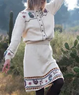 Falda midi de tejido de punto color blanco marfil, confeccionada en lana merino, con diseño bordado a mano de motivos paisley y guardas geométricas en tonos marrones y celestes. Cuenta con cintura elástica.