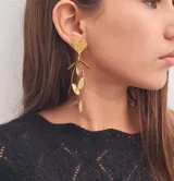 Aros colgantes dorados con forma de corazón y hojas.