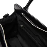 Cartera de mano tipo tote marca XL, color negro, confeccionada en material símil cuero con textura granulada. Presenta doble asa superior, correa ajustable y extraíble, y un bolsillo frontal con cierre metálico.