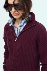 Sweater de tejido de punto color bordó, con cuello alto, cierre frontal parcial y mangas largas.