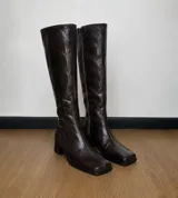 Bota alta de caña recta confeccionada en cuero con efecto arrugado color marrón oscuro, de punta cuadrada y tacón ancho.