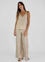 Pantalon de corte recto y pierna ancha, confeccionado en lino color beige. Presenta un diseño de tiro medio con aberturas laterales en el ruedo y detalle de bordes desflecados.