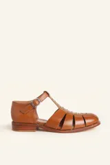 Sandalias de cuero color marrón, tipo romanas, con talón cerrado, tira en T con detalles de tachas metálicas, aberturas laterales y cierre de hebilla ajustable. Tienen tacón bajo de madera.