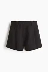 Short negro de tiro alto con pliegues tableados, bolsillos al bies y corte holgado.