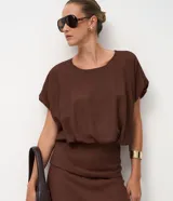 Blusa corta de estilo balonê confeccionada en tejido de viscosa, con mangas cortas amplias, escote redondo y ruedo fruncido que genera un efecto voluminoso.