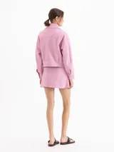 Minifalda de cuero ovino graneado negro, de tiro medio-alto y silueta evasé, con forrería interna y cinturón integrado con hebilla y ojalillos metálicos.