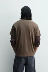 Camiseta de manga corta y cuello redondo, color marrón oscuro, con estampado frontal que dice "BOWERY ELECTRIC" en tipografía desgastada.