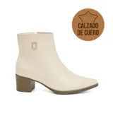 Bota corta de cuero negro con taco cuadrado y punta fina. Presenta un detalle metálico dorado con logo en el lateral superior y cierre lateral.