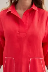 Vestido largo lila de lino, con cuello camisero, mangas cortas, bolsillos frontales con costuras a contratono y aberturas laterales.