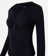 Body negro de rib, con cuello polo, escote en V, mangas largas y frunces en el busto. Cierre inferior con botones a presión.