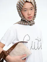 Remera blanca de corte oversize con la palabra 'Cute' escrita en el frente mediante apliques de strass brillantes.