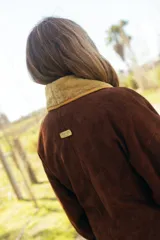 Chaqueta corta de gamuza marrón, con amplio cuello smoking y solapas de corderito en color mostaza, diseño cruzado con doble abotonadura, mangas amplias y bolsillos exteriores.
