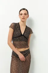 Top de encaje negro con escote en V y tiras de terciopelo. Es de manga corta y corte ajustado.