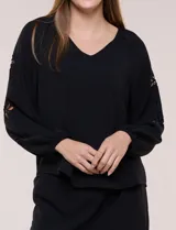 Blusa azul de corte holgado y fluido, con escote en V y mangas largas raglán que presentan detalles de calados con forma de flores y puños elastizados.