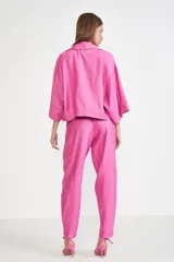 Pantalón de vestir rosado con corte holgado, tiro alto, bolsillos laterales con cierre y cierres en los tobillos.