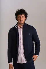 Cardigan de punto color azul marino, con cuello alto, cierre frontal completo y puños acanalados. Presenta el logo de la marca bordado en el pecho.
