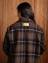 Chaqueta de paño con diseño de cuadros, corte recto, solapas clásicas, cierre frontal con botones y bolsillos laterales con solapa.