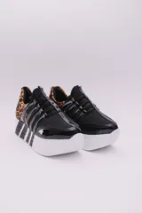 Zapatillas urbanas negras con plataforma blanca y detalles a rayas en el talón y la suela. Presentan un diseño con múltiples tiras elásticas en el empeine y puntera charolada.