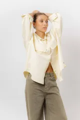 Sobrecamisa de gabardina liviana color crema, con corte oversize, cuello clásico, cierre frontal con botones a presión y dos bolsillos delanteros con solapa.