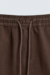 Bermuda de algodón color beige claro, de corte regular fit, con cintura elástica ajustable mediante cordón. Presenta bolsillos laterales y un bolsillo trasero de vivo.