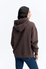 Canguro de algodón con capucha y bolsillo frontal, de diseño urbano y corte holgado. Presenta un parche rectangular en el pecho con detalles gráficos y el logo de la marca Mistral.