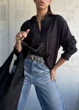 Camisa negra de corte holgado con detalles de encaje floral en la parte frontal y en los puños, cierre frontal con botones y cuello clásico.