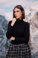 Polera de tejido de punto fino color negro, con cuello alto, mangas largas y terminaciones con detalle de ondas en cuello y puños.