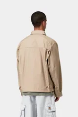 Campera Postal Jacket de Carhartt WIP en color negro, con cierre frontal de cremallera, cuello clásico, bolsillos laterales y un bolsillo con cierre en el pecho adornado con el parche del logo de la marca.