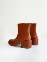 Bota de caña media color óxido, confeccionada en cuero, con plataforma y taco cuadrado texturizado, punta cuadrada y cierre lateral.