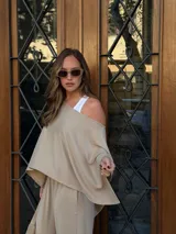 Blusa de lanilla color beige, con diseño de un solo hombro y corte holgado tipo capa.