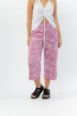 Pantalón de corte culotte y tiro medio, confeccionado en viscosa con estampado de hojas blancas sobre fondo color miel. Presenta una silueta amplia y fluida, con cintura elástica en la parte posterior y bolsillos laterales.