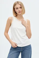 Musculosa blanca de algodón, de corte ajustado, con cuello redondo y detalles de broderie en los bordes.