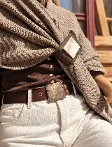 Cinturón de cuero marrón con hebilla metálica cuadrada de diseño artesanal y pasadores metálicos laterales.