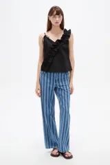 Musculosa de algodón color negro con escote en V profundo, tirantes finos y un volado diagonal fruncido que cruza desde el hombro izquierdo hasta el dobladillo.