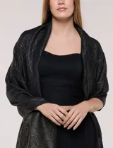 Pashmina rectangular negra con diseño jacquard de rombos, destellos metalizados dorados y flecos anudados en los extremos.